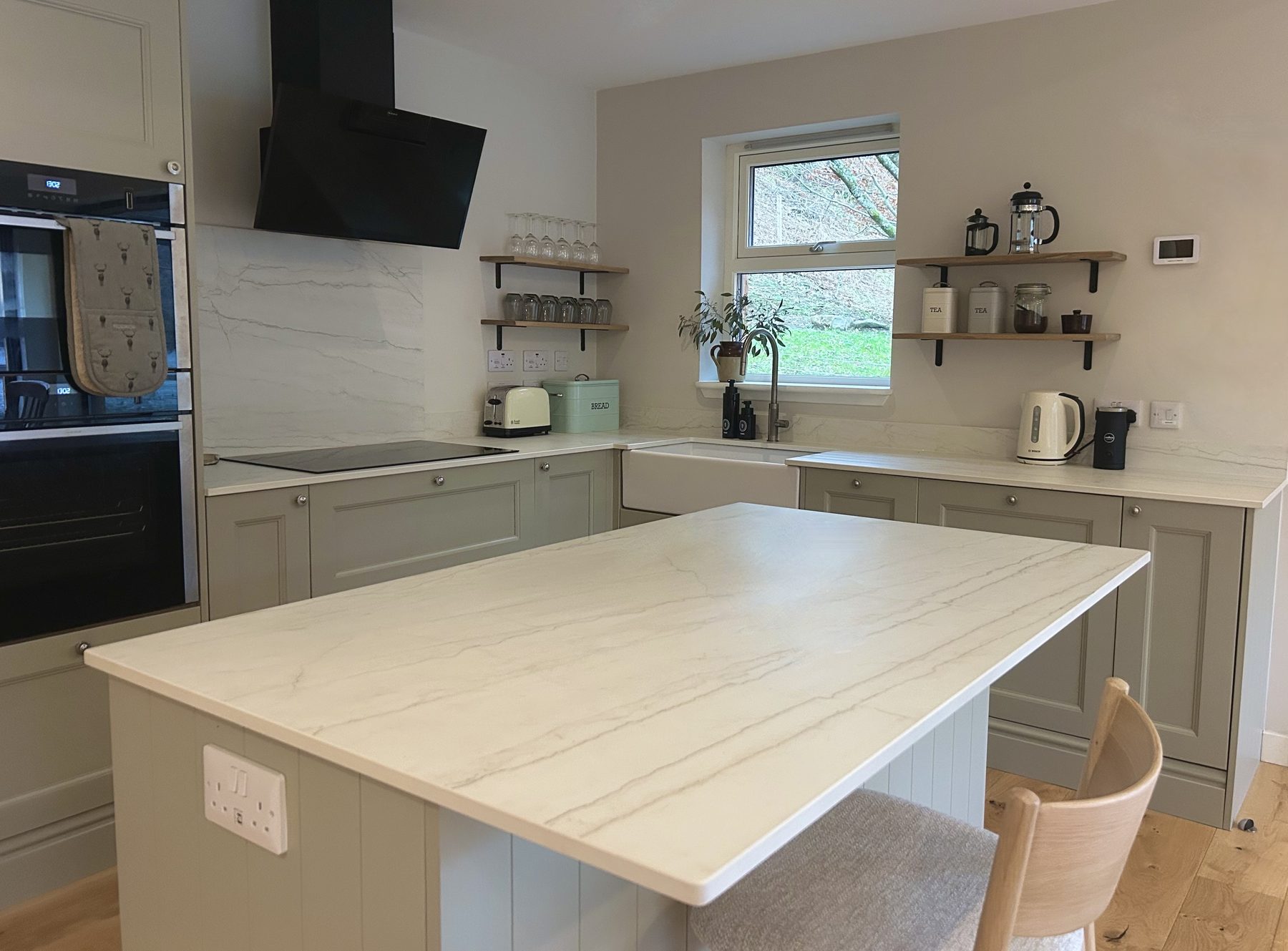 Sage green kitchen with stone-effect island