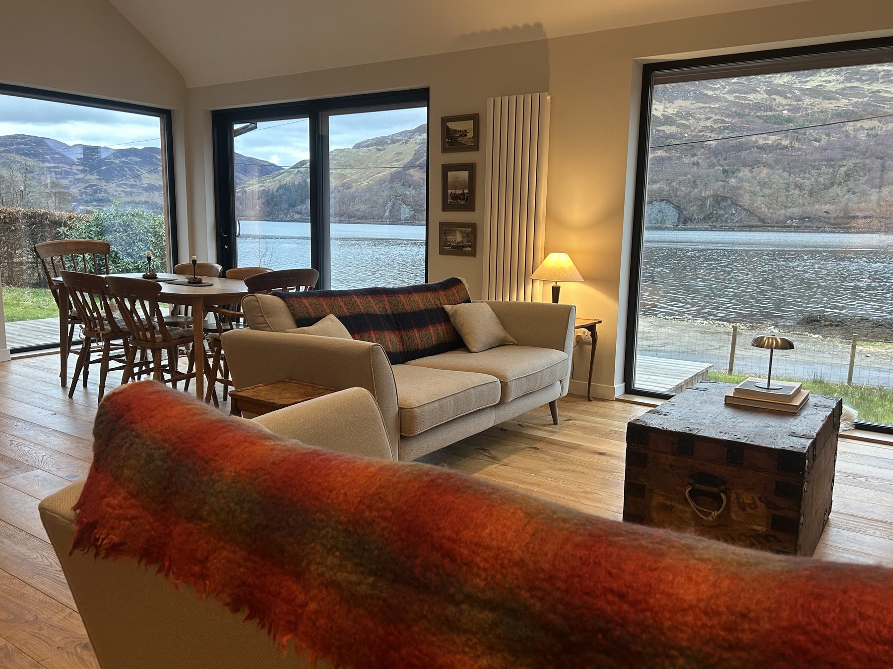 Open-plan living room with full loch views through three large windows