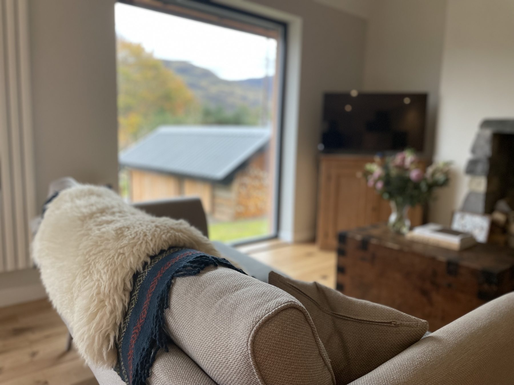 Sheepskin throw on sofa arm, autumn hills through the window